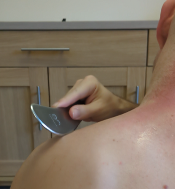 man using the Myoscraper on his neck and shoulders